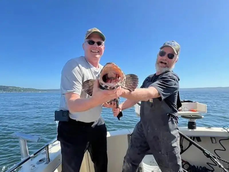 Guests holding a salmon during a Puget Sound fishing charter near Seattle.